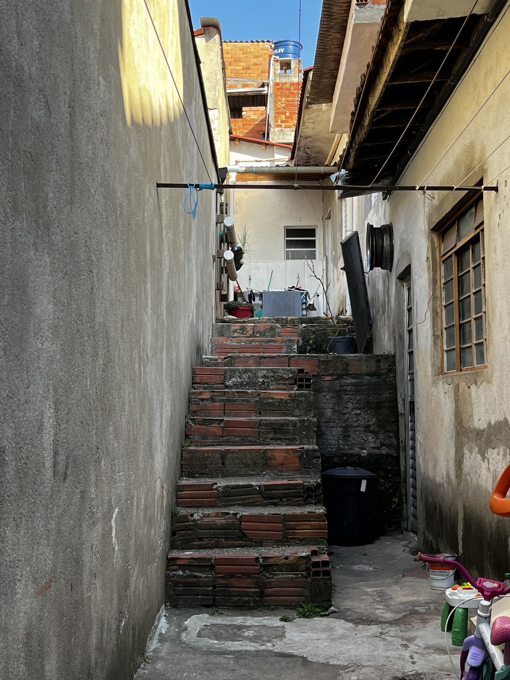 Escada de tijolos aparentes em um corredor estreito da casa onde morávamos